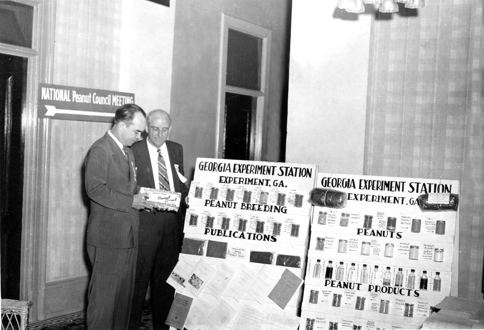 Historic photo of 2 people standing next to posters in Stuckey.
