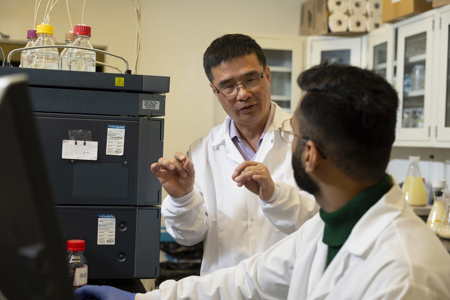 Professor and researcher in the lab talking to each other.