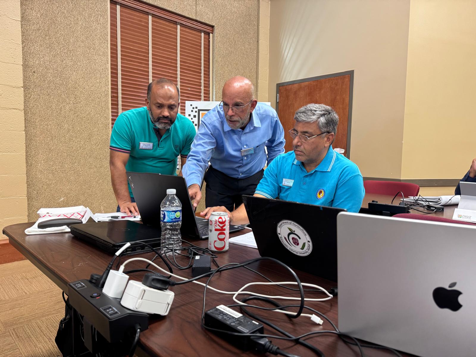 Professor standing over students using laptops.