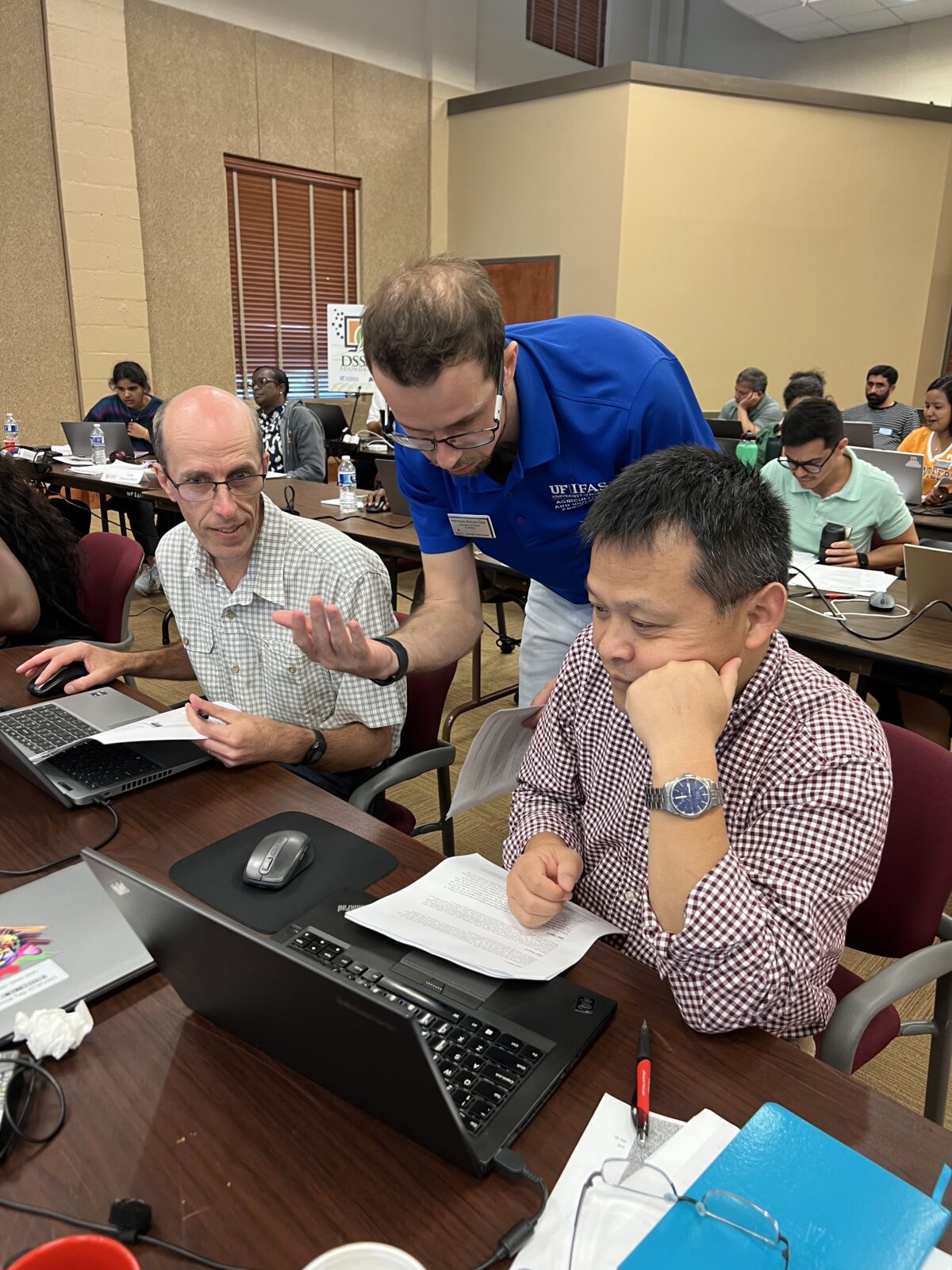Professor standing over students using laptops.